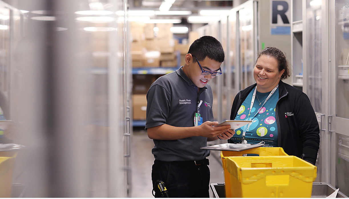 Two people in a stock room reviewing items on a clipboard.